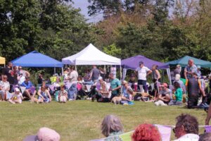 a crowd of people at an event. gazebos are seen in the background