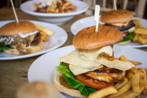 three burgers are shown on plates with chips 