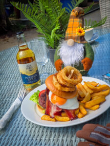 a towering burger is shown with onion rings on top