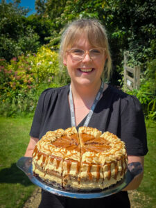 a cafe staff member is shown smiling and holding up a huge cake