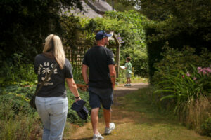 two people are seen walking through the gardens, their backs are to the camera, a child can be seen ahead of them out of focus